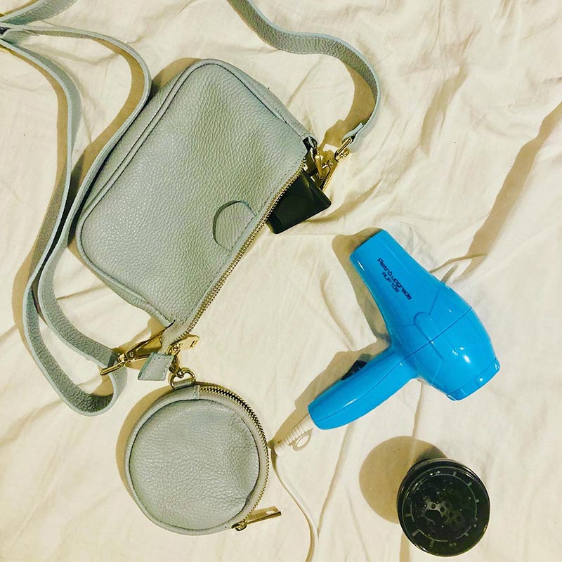 Il mini phon al fianco di una borsetta ad evidenziarne le misure estremamente ridotte. Perfetto per viaggiare e per fare sport, all'interno un diffusore ed un beccuccio.